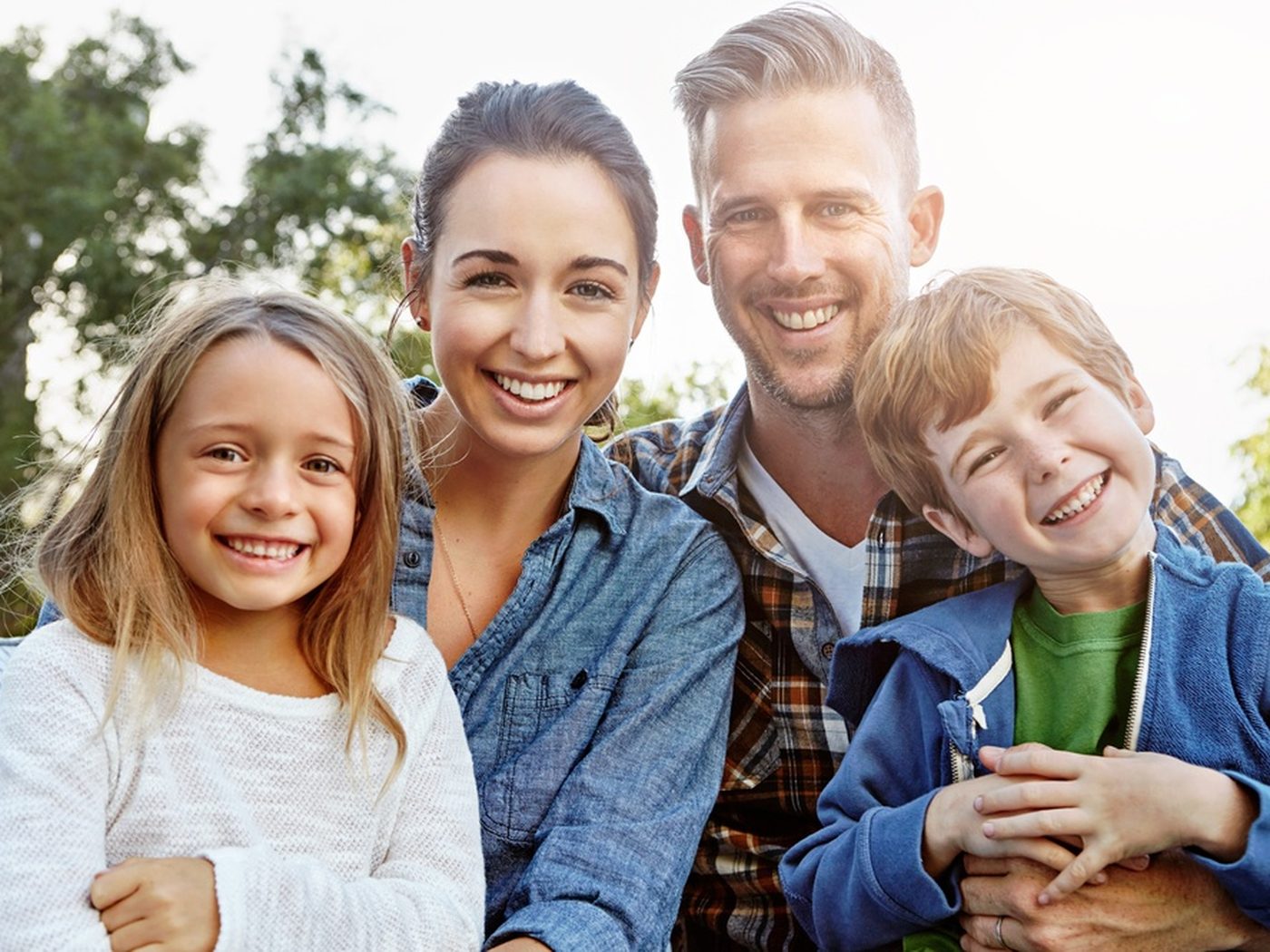 Família sorrindo ao ar livre — pais e duas crianças