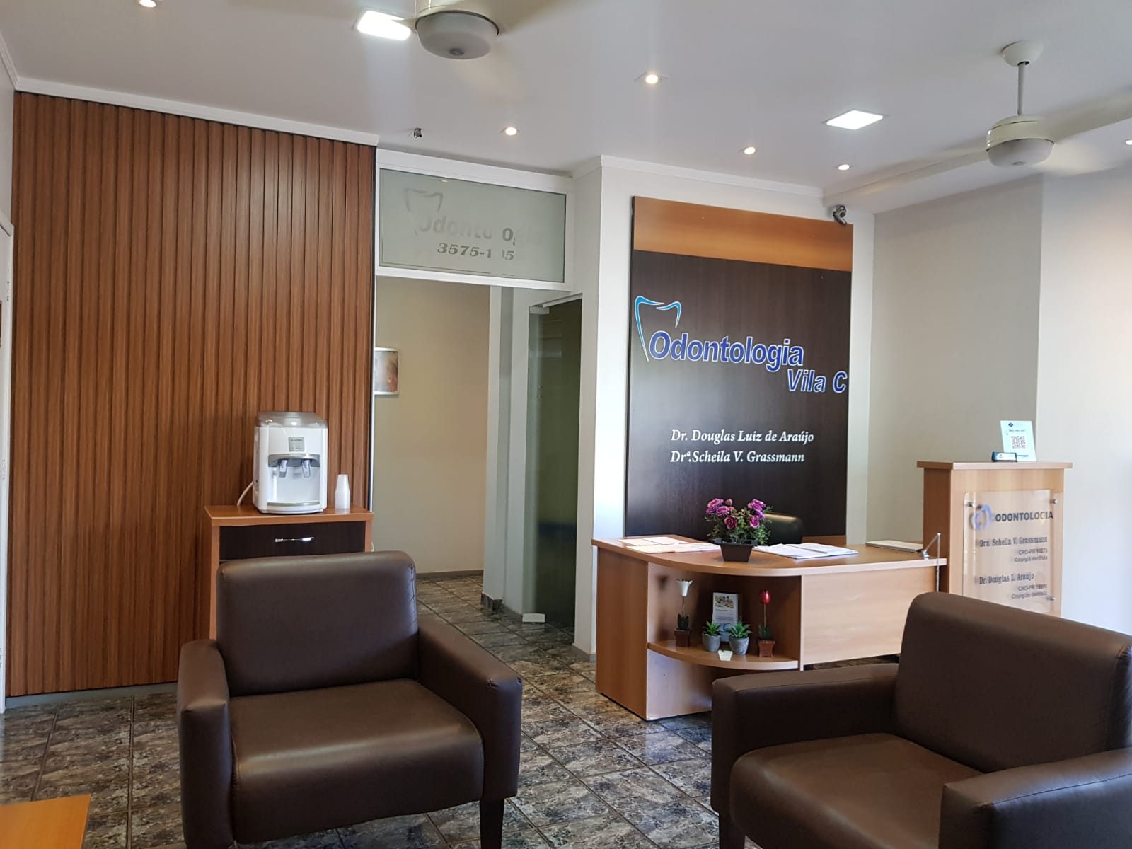 Recepção da Odontologia Vila C, com balcão de atendimento e a identificação dos cirurgiões-dentistas